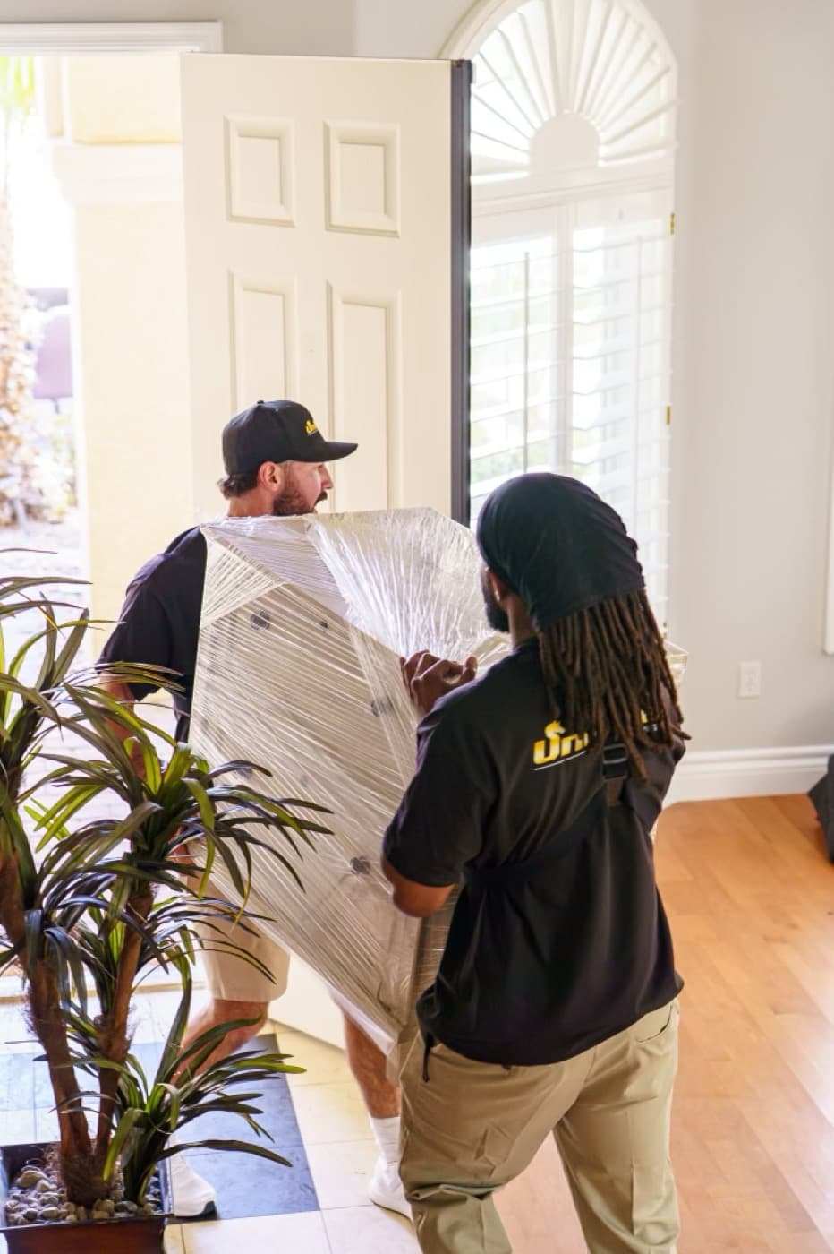 Unicorn Moving crew carefully carrying a shrink-wrapped piece out of a Las Vegas home